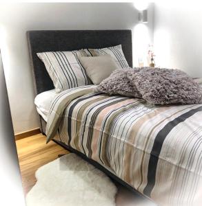 een slaapkamer met een bed met gestreepte lakens en kussens bij Vila Elsa 1 S13 in Zlatibor