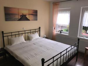 een slaapkamer met een bed met witte lakens en 2 ramen bij Ferienwohnung Egerten in Wehr