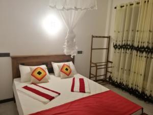 a bedroom with a large bed with red and white pillows at Flip Flop Inn Mirissa in Mirissa