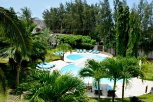 Amani Residence Beverly Suites في ماليندي: مسبح والكراسي الزرقاء والنخيل