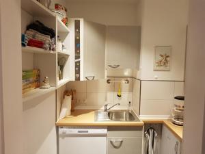 una pequeña cocina blanca con fregadero y estanterías en Christels Gästewohnung en Bünde