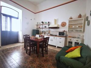 a kitchen and dining room with a table and a green couch at Etesia Vacation Home in Acitrezza