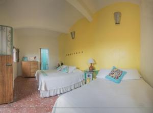 a bedroom with two beds and a yellow wall at Boca del Monte by Diablo y la Sandia B&B in Oaxaca City