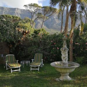 two chairs and a fountain in a yard with mountains in the background at 11 Deerpark Drive East in Cape Town