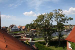 a view of a river with a tree and houses at Amtmannshaus Greetsiel in Greetsiel