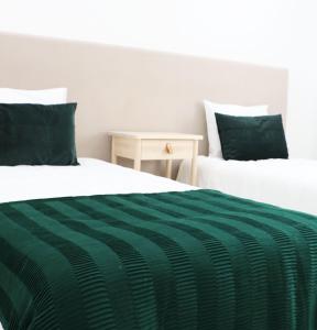 2 Betten mit grüner und weißer Bettwäsche und einem Tisch in der Unterkunft COLD CITY HOUSE in Guarda