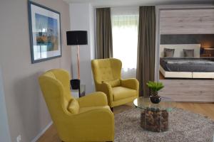 ein Wohnzimmer mit 2 gelben Stühlen und einem Bett in der Unterkunft Waldstudio Comfort in Simmerath