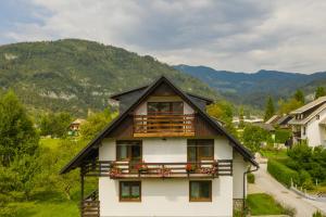 a house with a balcony and mountains in the background at Apartment Ana in Bohinj