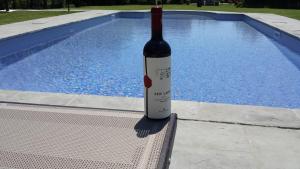 a bottle of wine sitting on a bench next to a swimming pool at Casale l'Antico Carro in Cortona