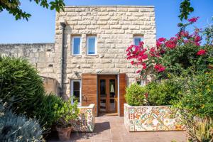 una casa de piedra con una puerta y algunas flores en THE LOFT en Żabbar