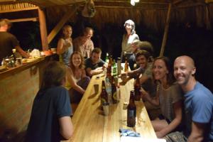 eine Gruppe von Menschen, die mit Weinflaschen um einen Tisch sitzen in der Unterkunft Maracumbo Lodge in Mompiche