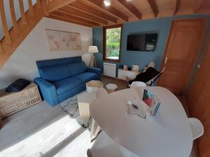 a living room with a blue couch and a table at Chalet calme et cosy entre terre et mer in Berck-sur-Mer