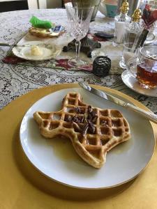 a waffle on a white plate on a table at The Lancaster Manor Bed and Breakfast in Gainesville