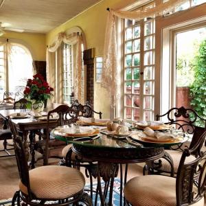 un comedor con mesas, sillas y ventanas en The Lancaster Manor Bed and Breakfast en Gainesville