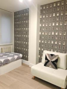 - une chambre avec un lit et une chaise en face d'un mur dans l'établissement Apartamento Plaza del Pilar, à Saragosse