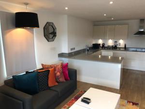a living room with a couch and a kitchen at PRESTIGE 2 BED BALCONY APARTMENT in Abbey Wood