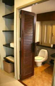 a bathroom with a toilet and a wooden door at Palita Lodge - SHA Plus in Haad Rin