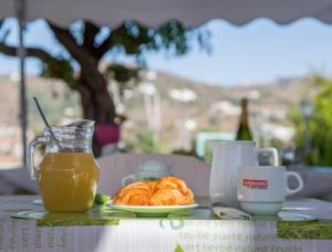 uma mesa com um prato de croissants e um copo de sumo de laranja em Alojamiento Colina del Sol em Torrox