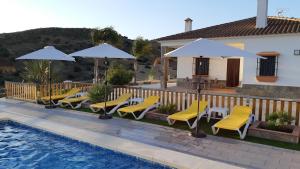 una piscina con sillas y sombrillas junto a una casa en Villa Rural El Mirador, en Álora
