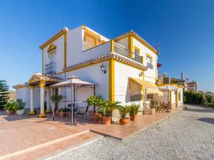 a yellow and white house with tables and chairs at Alojamiento Colina del Sol in Torrox