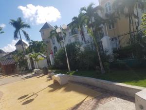 un grand bâtiment avec des palmiers devant lui dans l'établissement ROSI Ocean Sand Hotel Apt (@Sandcastles), à Ocho Rios