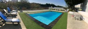 a swimming pool in a yard with chairs around it at Laurel Beach House in Lourinhã