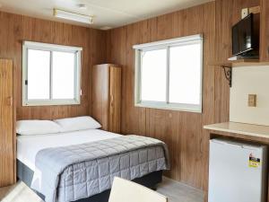 a small bedroom with a bed and two windows at Stuarts Point Holiday Park in Stuarts Point