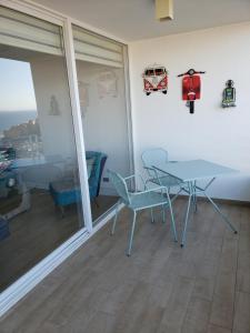 a dining room with a table and chairs and glass doors at DEPARTAMENTO EDIFICIO MARES DE MONTEMAR in Concón