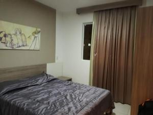 a bedroom with a bed and a window with a curtain at Caldas Novas Riviera in Caldas Novas