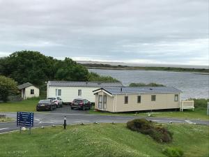 a house and cars parked next to a lake at Lakes Retreat in Millom