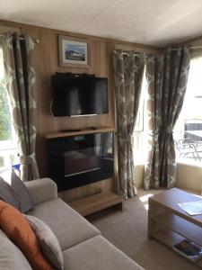 a living room with a flat screen tv and curtains at Lakes Retreat in Millom