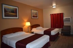 a hotel room with two beds and a red curtain at El Cajon Inn & Suites in El Cajon