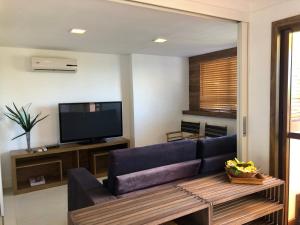 a living room with a blue couch and a tv at Cobertura Barra de São Miguel in Barra de São Miguel