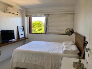 a white bedroom with a bed and a window at Cobertura Barra de São Miguel in Barra de São Miguel +11 photos