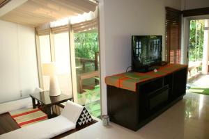 a living room with a tv and a couch and a table at Palita Lodge - SHA Plus in Haad Rin