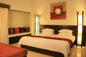 a bedroom with two beds and a clock on the wall at Palita Lodge - SHA Plus in Haad Rin
