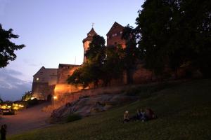 people sitting in the grass in front of a castle at Hotel LACIN in Nürnberg
