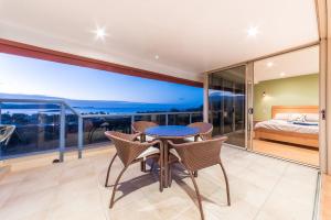 a bedroom with a balcony with a bed and a table and chairs at VIEWS ON ELSHEBY in Airlie Beach