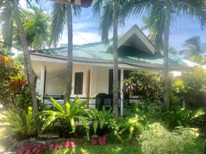 ein weißes Haus mit Palmen davor in der Unterkunft Paguia’s Cottages in Mambajao