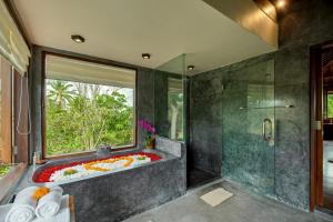 ein Badezimmer mit einer Badewanne und einem großen Fenster in der Unterkunft Villa Atas Awan in Payangan