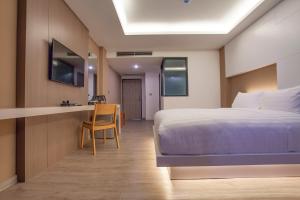 a bedroom with a bed and a desk with a chair at The Zense Boutique Hotel in Phitsanulok