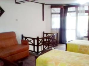 um quarto com uma cadeira, uma cama e janelas em Gazebo Beach Hotel em Sanur