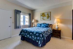 Schlafzimmer mit einem Bett mit blauer Bettdecke und einem Fenster in der Unterkunft Sand & Sea: Sailor's Retreat (400) in Seaside
