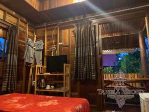 een slaapkamer met een bed, een televisie en een raam bij Taksila Resort ฏักร์ศิลารีสอร์ท in Ban Nong Lup