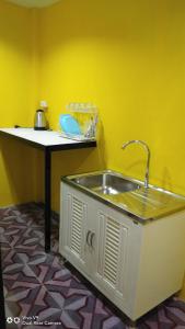 eine Küche mit einem Waschbecken in einer gelben Wand in der Unterkunft Baan Asree บ้านอัสรี in Ao Nang Beach