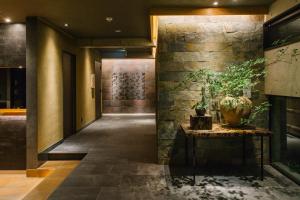 a hallway with a stone wall and a table with a potted plant at Higashiyama Shikikaboku in Kyoto