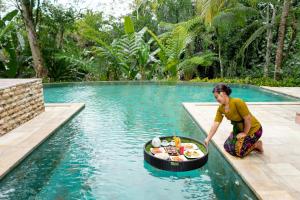 Eine Frau, die im Wasser neben einem Pool sitzt. in der Unterkunft Villa Atas Awan in Payangan