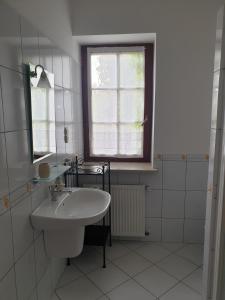 a white bathroom with a sink and a window at Żabie Oko in Kruklanki