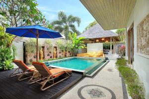 - une piscine avec 2 chaises et un parasol dans l'établissement The Sari Balangan Villa, à Jimbaran