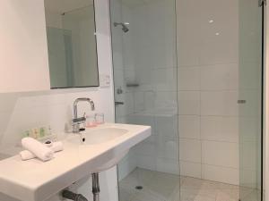 a white bathroom with a sink and a shower at Cosmopolitan Hotel Melbourne in Melbourne